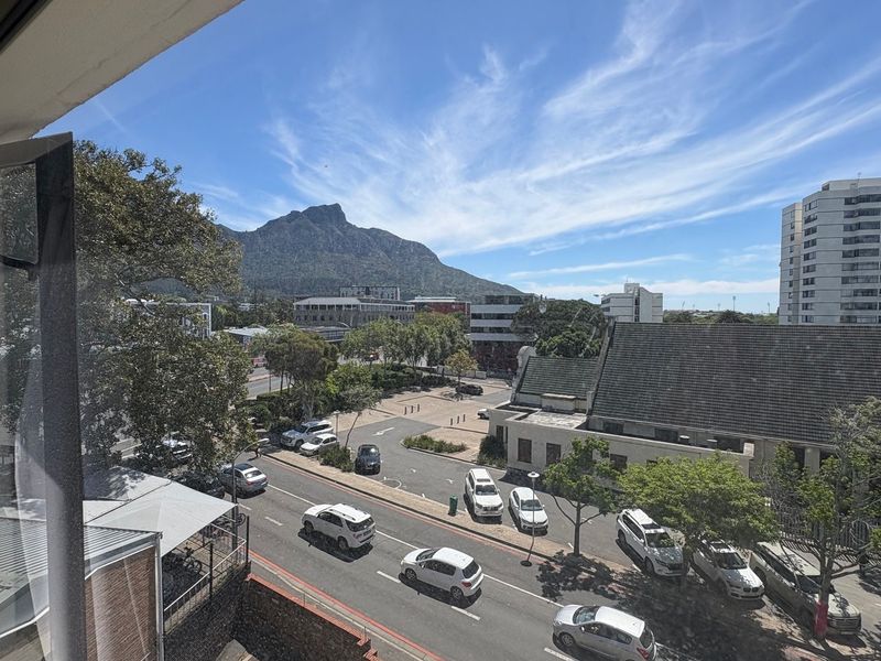 Elevated urban view overlooking the street, surrounding buildings, and mountain landscape from the property.