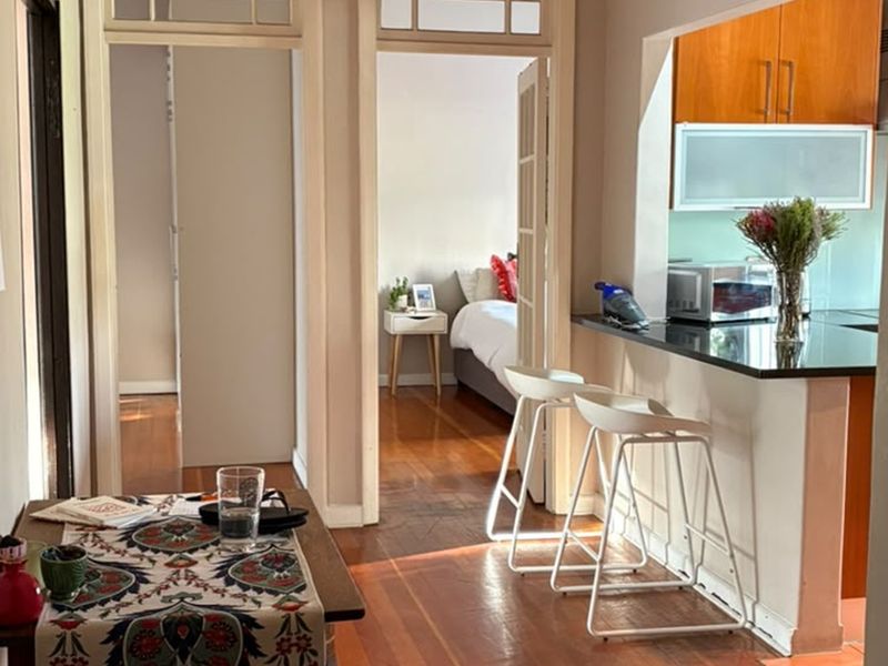 Open plan living area featuring hardwood flooring, a kitchen with granite countertops and breakfast bar, and access to adjacent rooms through classic doorways.