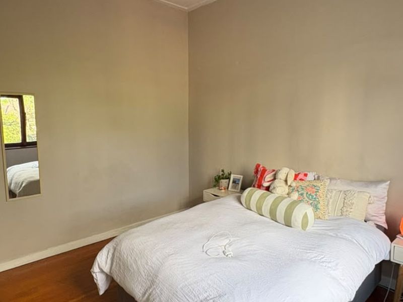 A simple bedroom featuring hardwood flooring and neutral wall tones, offering a clean and functional space.