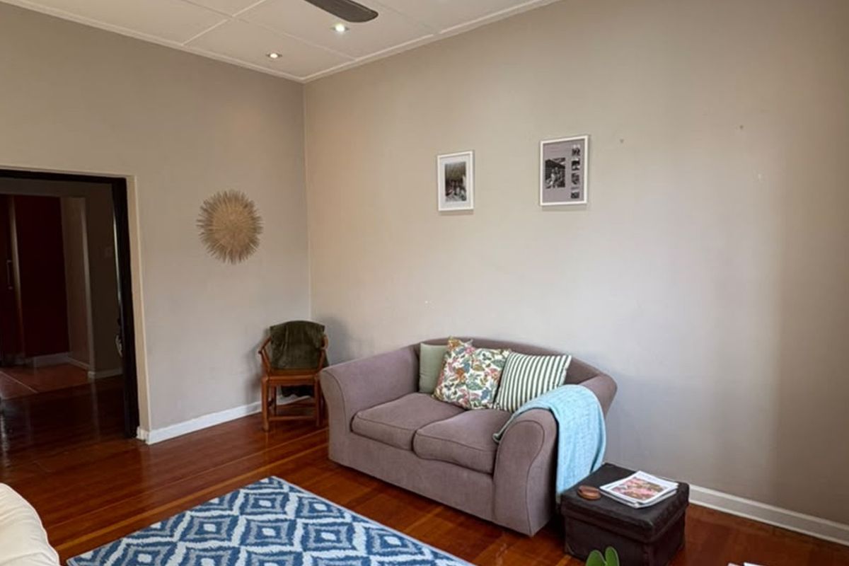 A living room featuring polished hardwood flooring, recessed ceiling lighting, and a ceiling fan, providing a neutral base for interior design.