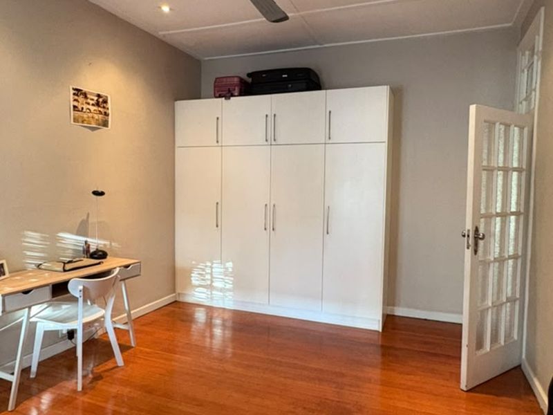 A bedroom featuring polished hardwood flooring, a large white built-in wardrobe, and a classic french door entrance.