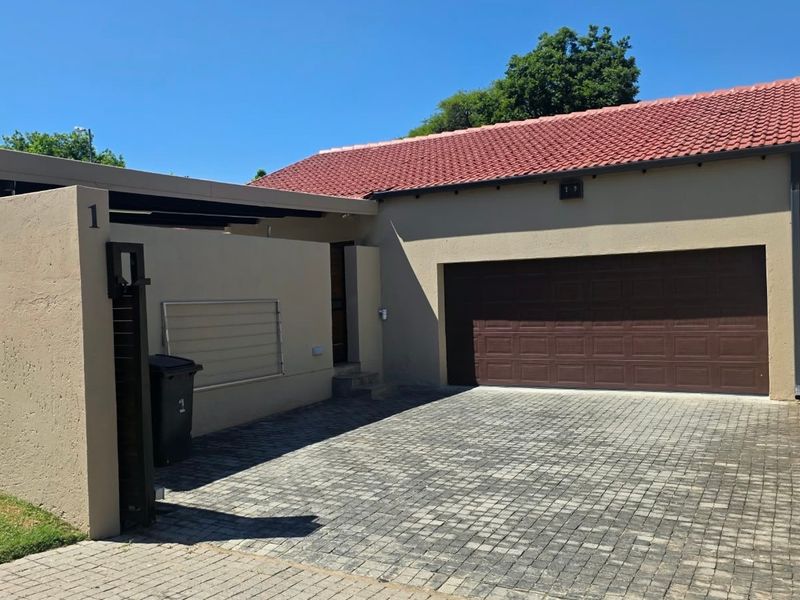 Front view of a cluster home featuring a paved driveway, double garage, and a covered entrance area with a tiled roof.