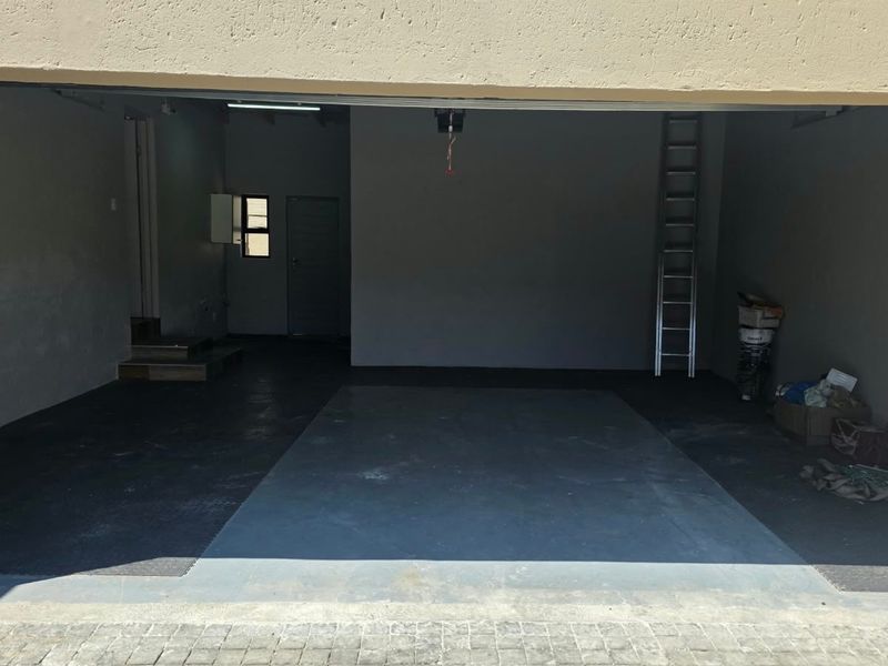 A spacious, empty double garage featuring concrete flooring, internal access door, and overhead lighting, providing ample storage or vehicle parking space.
