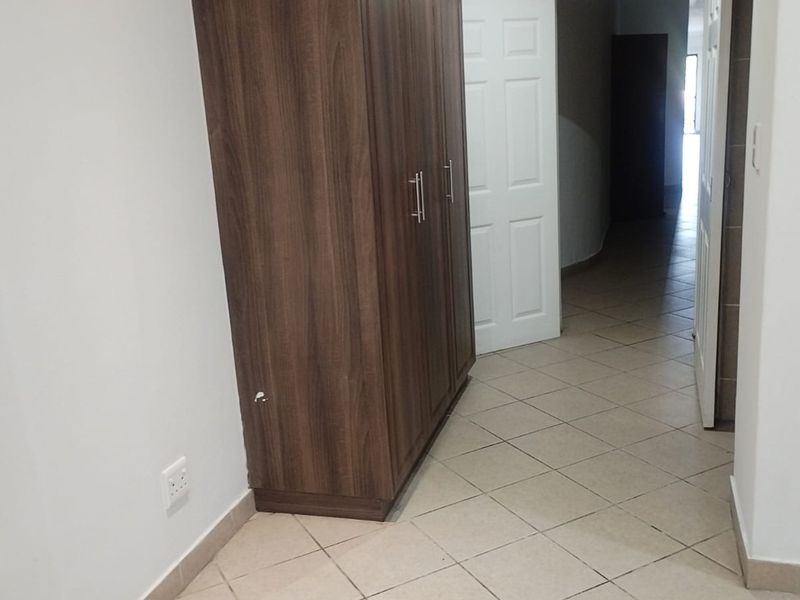 A functional hallway featuring tiled flooring and a built-in wooden cupboard, providing access to adjacent rooms.