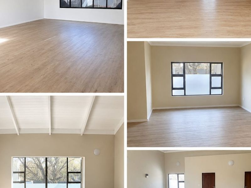 A bright and spacious office area featuring modern laminate flooring, exposed beam ceilings, and large aluminium-framed windows providing ample natural light.