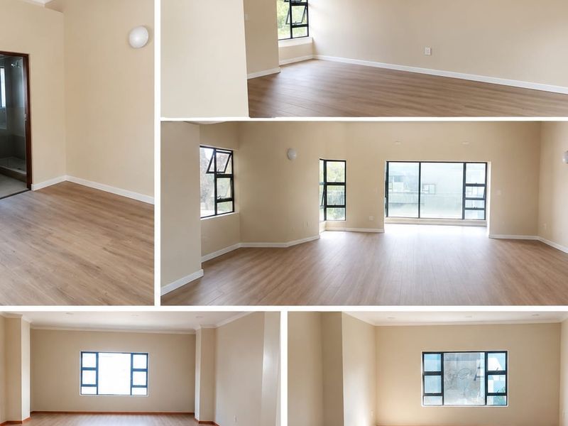 A spacious, empty office area featuring modern laminate flooring, neutral wall tones, and large aluminium-framed windows providing ample natural light.