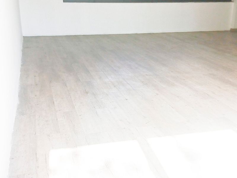 A bright, empty office space featuring light-toned laminate flooring and neutral walls, providing a clean and versatile environment for professional use.