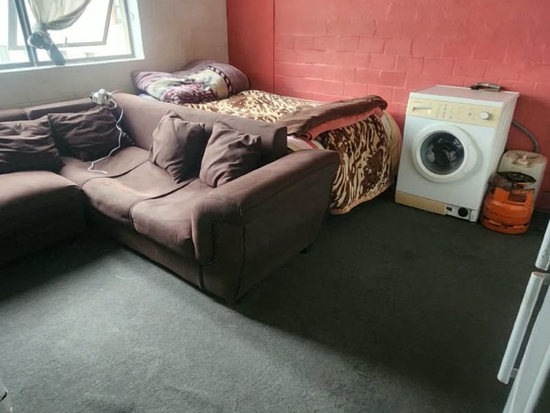 Open plan living area featuring exposed brickwork and carpeted flooring, requiring cosmetic updates to improve the overall aesthetic and condition of the space.