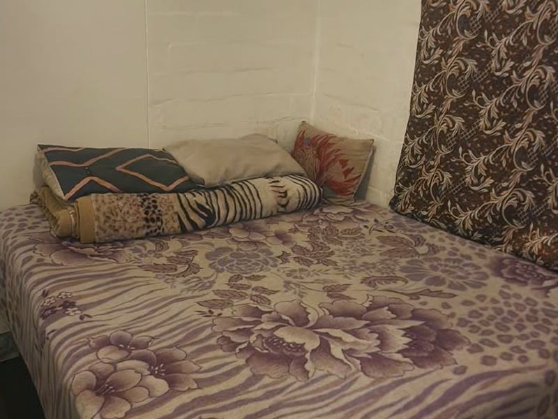 A compact bedroom space featuring painted brick walls, suitable for a single bed setup.