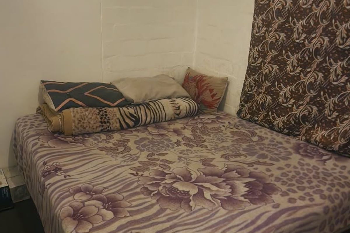 A compact bedroom space featuring painted brick walls, suitable for a single bed setup.