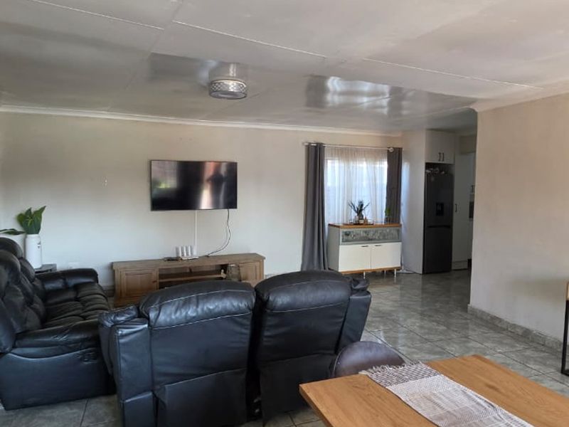 Open plan living area featuring tiled flooring and a coved ceiling, providing a functional space that connects to the kitchen area.