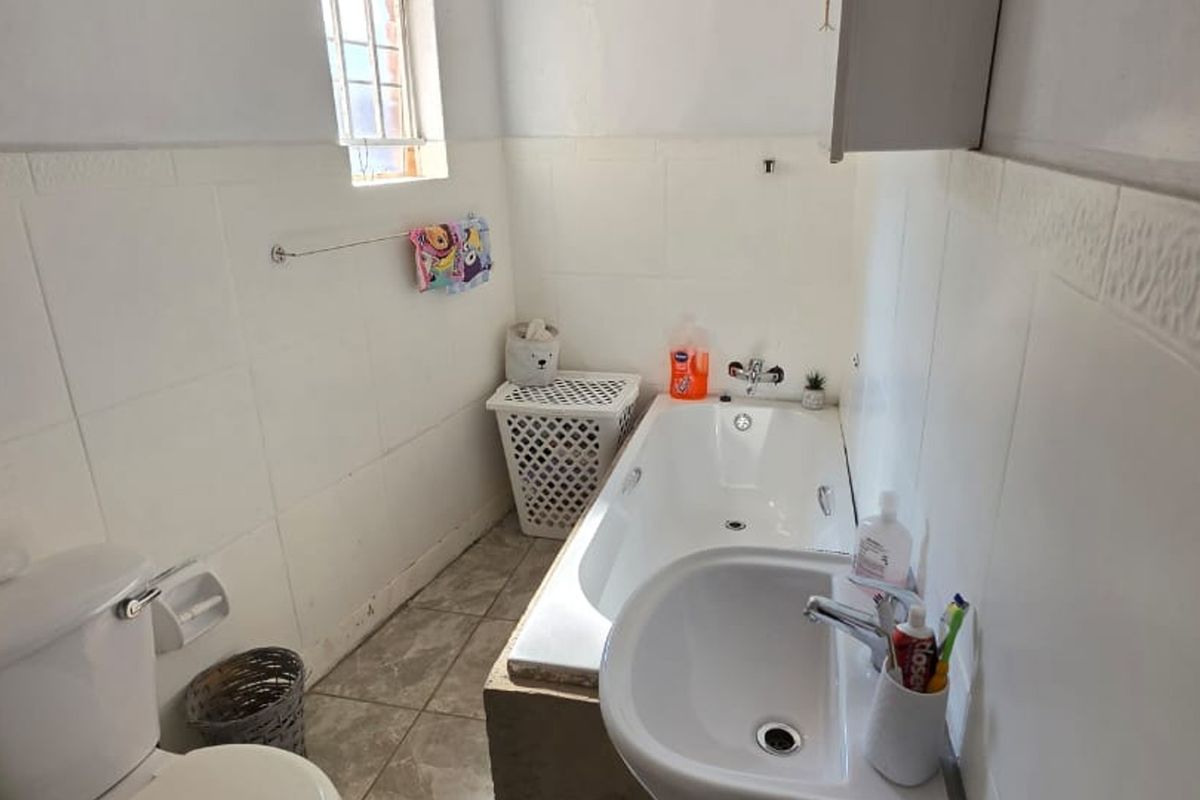 A functional bathroom featuring a standard bathtub, washbasin, and toilet with tiled finishes throughout.