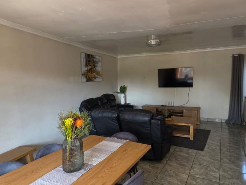 Spacious open-plan living and dining area featuring tiled flooring and neutral wall finishes, offering a versatile layout for comfortable family living.