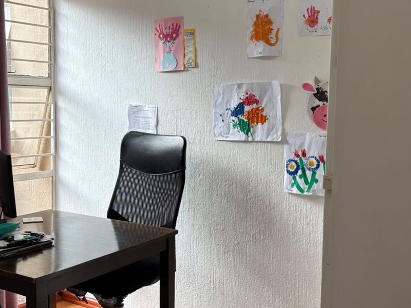 A functional home office space featuring laminate flooring and security burglar bars on the window.