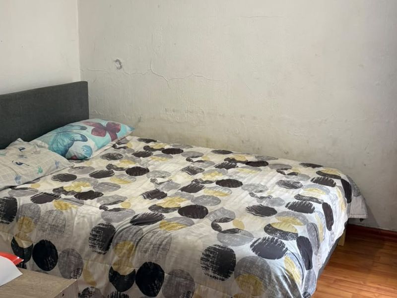 A bedroom featuring laminate flooring and walls requiring maintenance and cosmetic repair.