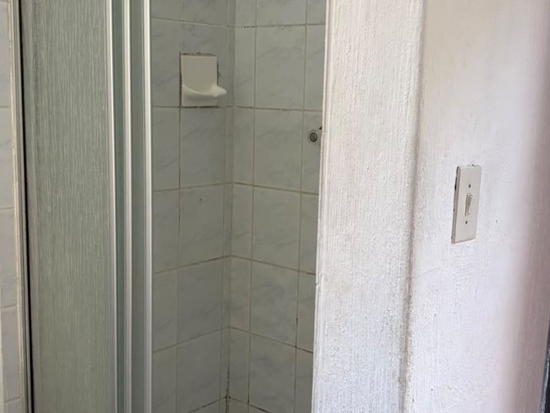 A compact shower area featuring tiled walls and a standard shower enclosure, requiring cosmetic updates to improve its overall condition.