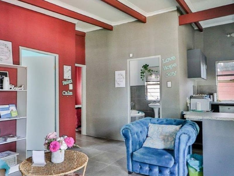Open plan living area featuring exposed ceiling beams, tiled flooring, and a functional kitchen space with built-in cabinetry and countertops.