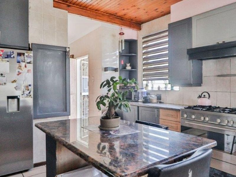 Kitchen featuring granite countertops, built-in cabinetry, gas stove with extractor fan, and a distinctive timber ceiling.