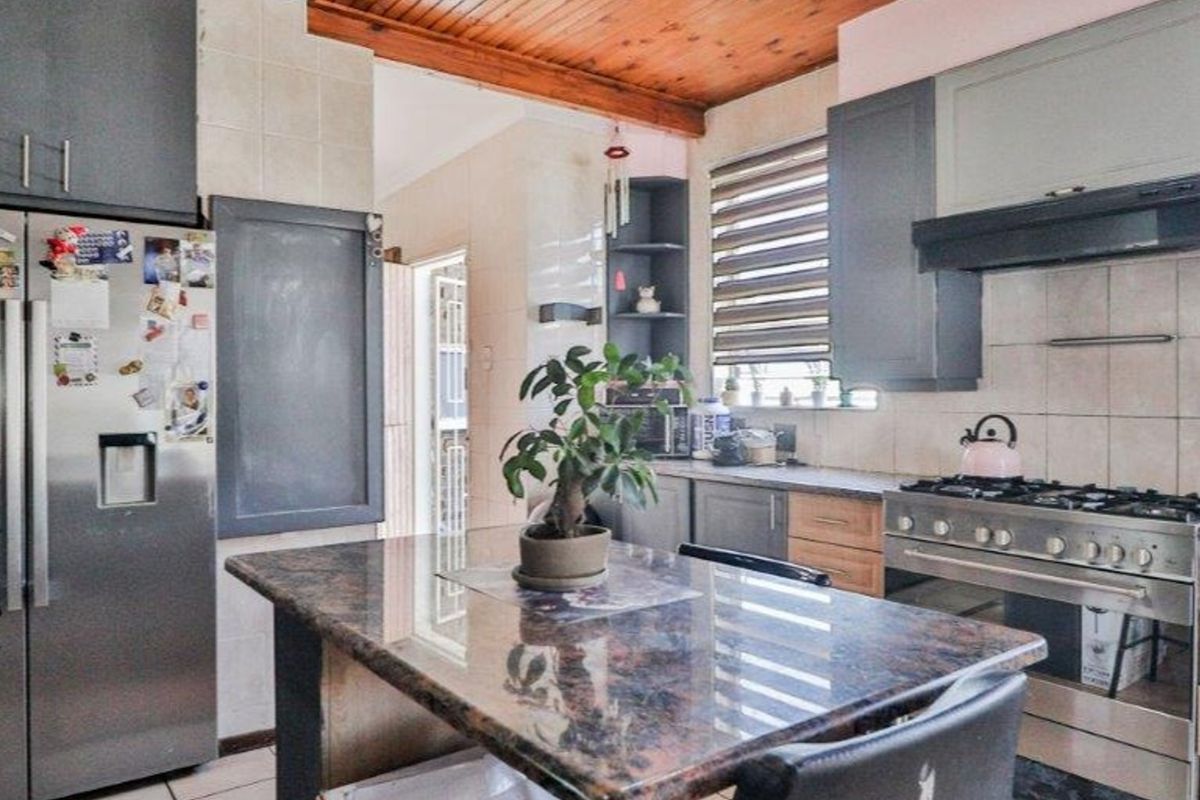 Kitchen featuring granite countertops, built-in cabinetry, gas stove with extractor fan, and a distinctive timber ceiling.
