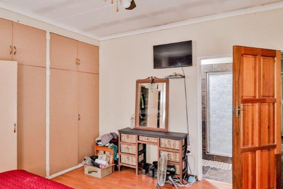 Bedroom featuring built-in cupboards, laminate flooring, and direct access to an en-suite bathroom area.