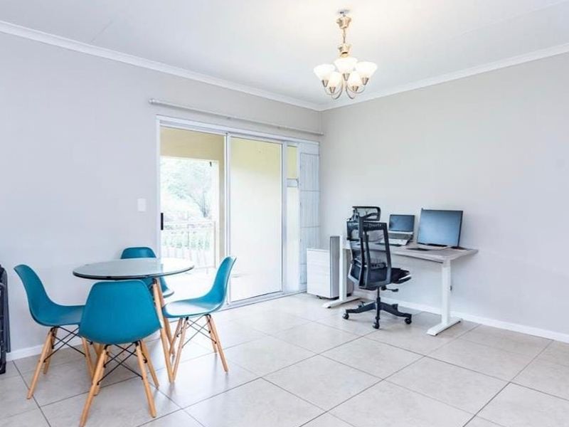 An open-plan living area featuring neutral tiled flooring, a central light fixture, and a sliding glass door providing access to an outdoor balcony.