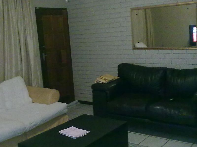A living room featuring painted brick walls and tiled flooring, providing a neutral base for potential interior updates.