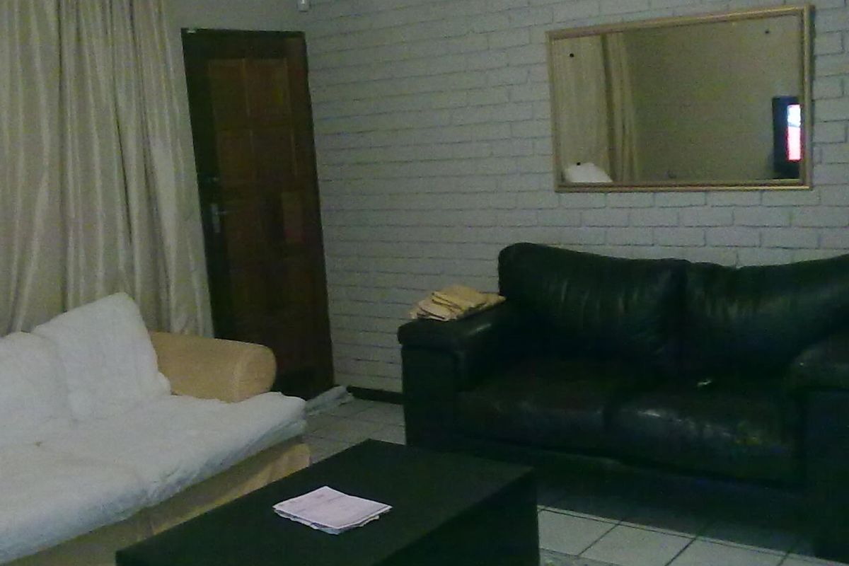 A living room featuring painted brick walls and tiled flooring, providing a neutral base for potential interior updates.