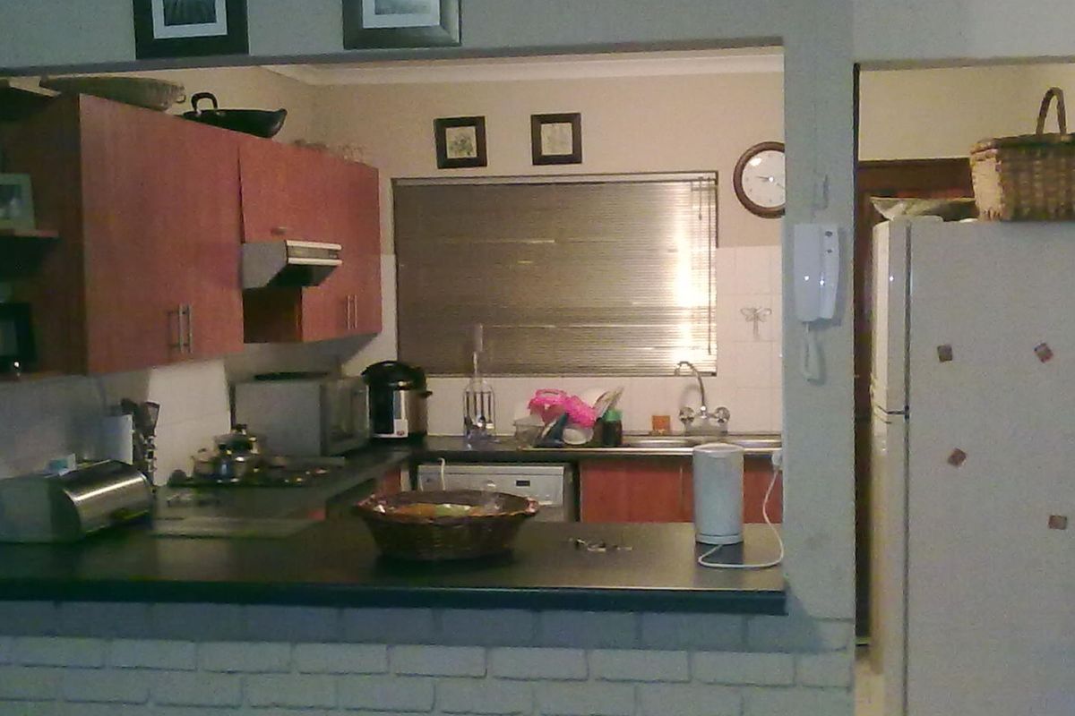 A functional kitchen featuring laminate cabinetry, dark countertops, a breakfast bar with a brick base, and a stainless steel sink.