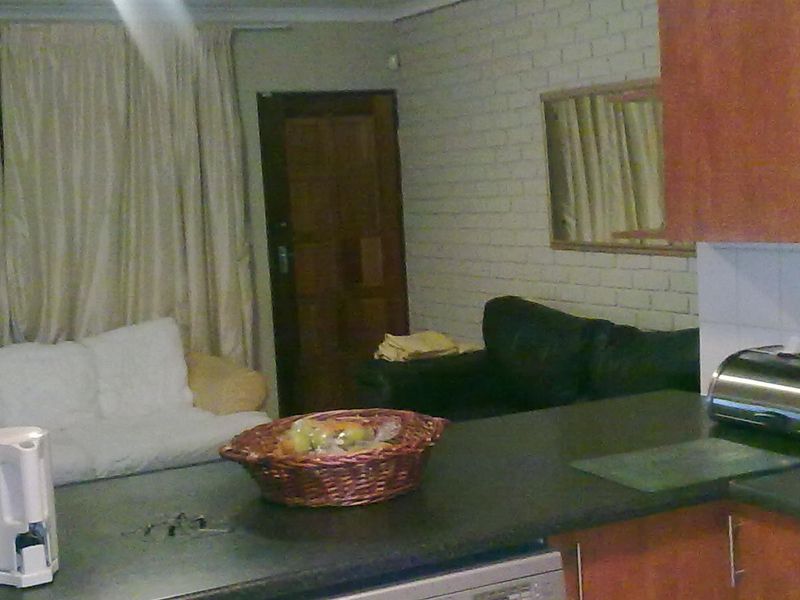 Open plan living area featuring a kitchen with laminate countertops and cabinetry, adjacent to a living space with brick wall detailing.