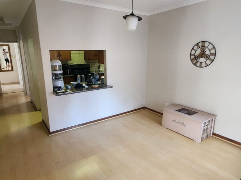 Open plan living area featuring laminate flooring and a convenient pass-through window connecting to the kitchen space.