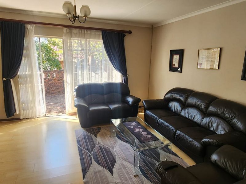 A comfortable living room featuring laminate flooring and a large sliding glass door that provides access to the outdoor patio area.