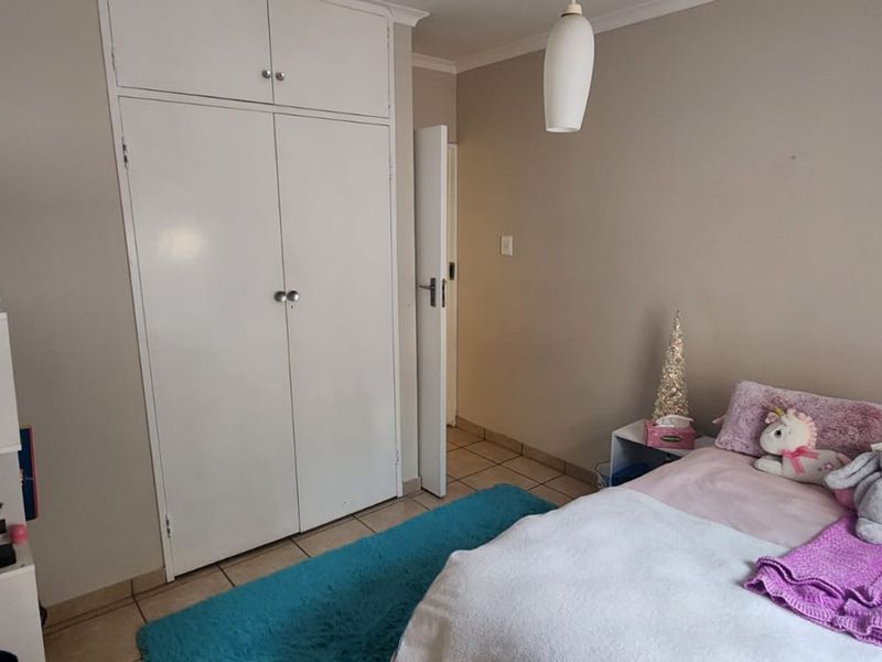 A functional bedroom featuring built-in cupboards, tiled flooring, and a coved ceiling, offering a neutral base for personalization.