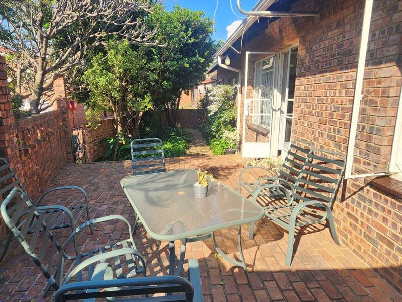 A private brick-paved patio area featuring a brick boundary wall and direct access to the townhouse interior.