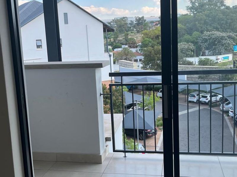 A private balcony featuring tiled flooring and a metal balustrade, offering an elevated view of the complex parking area.