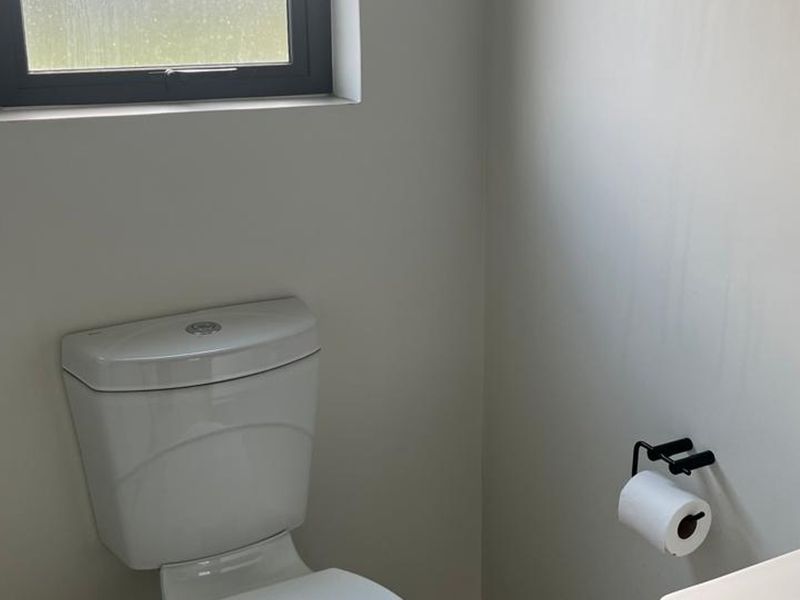 A clean and minimalist bathroom featuring a modern toilet and a window for natural light.