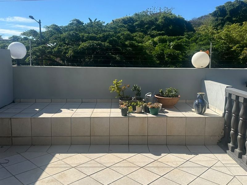 A spacious outdoor balcony featuring tiled flooring, a raised platform, and secure perimeter walling with electric fencing.