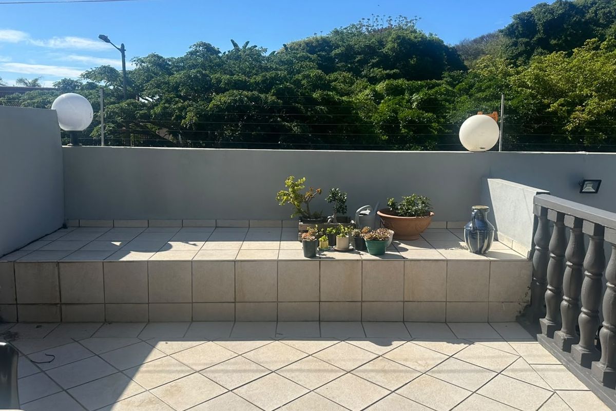 A spacious outdoor balcony featuring tiled flooring, a raised platform, and secure perimeter walling with electric fencing.