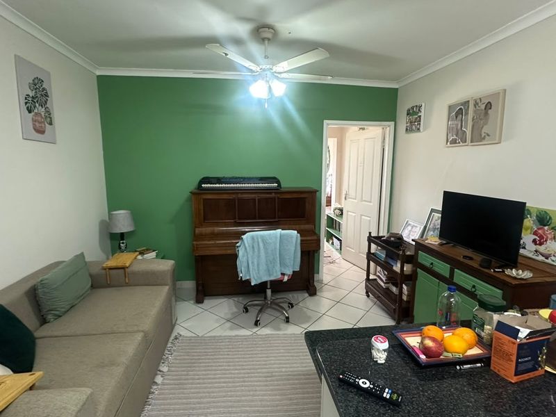 Open plan living area featuring tiled flooring and a ceiling fan, providing a functional space that connects to other areas of the apartment.