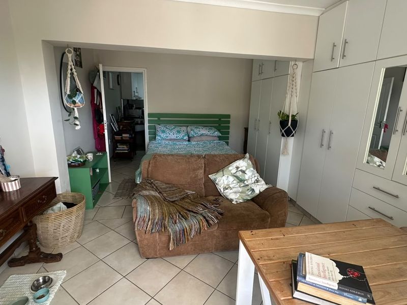 A bedroom featuring tiled flooring and extensive built-in cupboards with integrated mirrors, providing ample storage space.