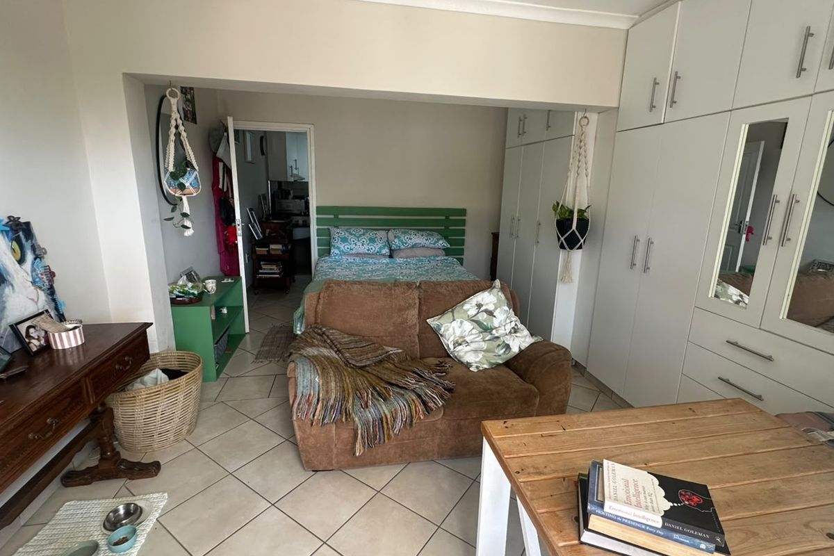A bedroom featuring tiled flooring and extensive built-in cupboards with integrated mirrors, providing ample storage space.