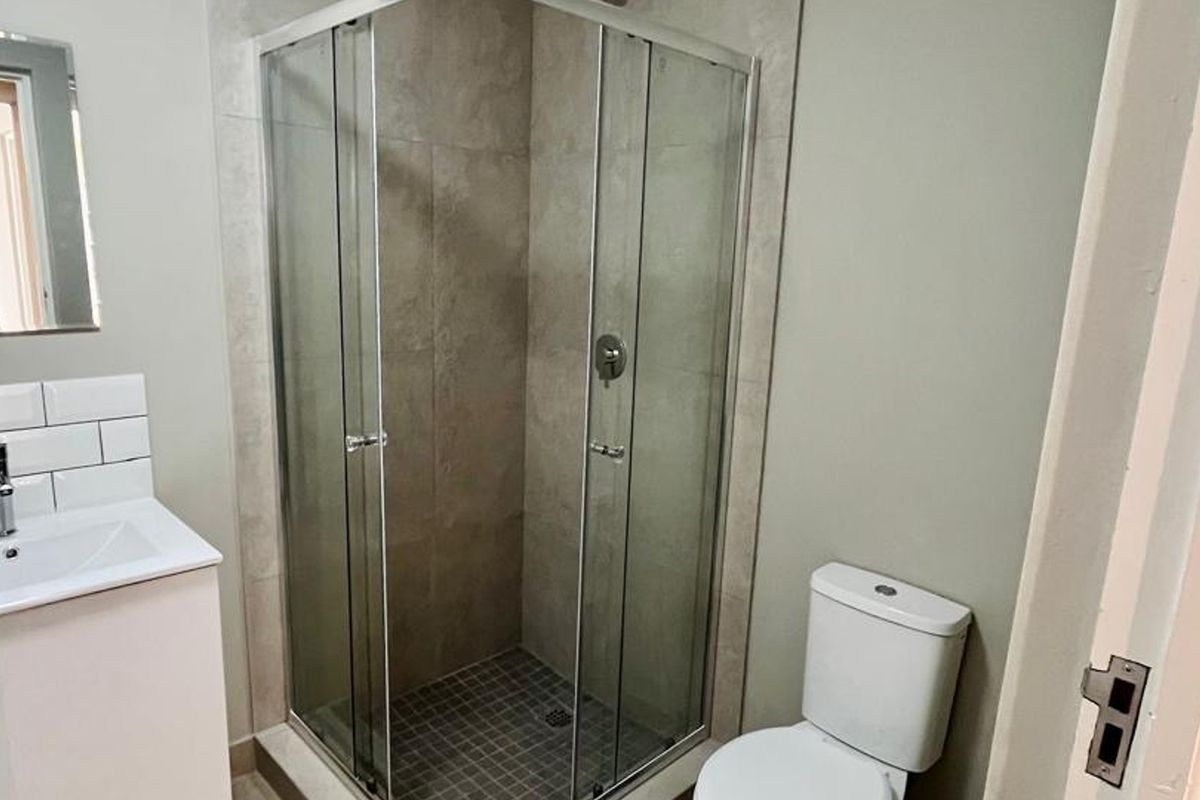 A modern bathroom featuring a glass-enclosed shower, a vanity basin with a mixer tap, and a standard toilet.