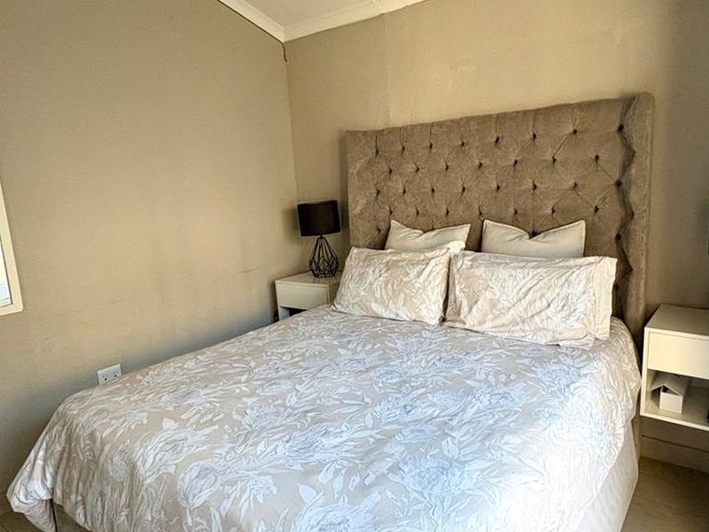 A neutrally decorated bedroom featuring a tufted headboard and built-in bedside shelving units.