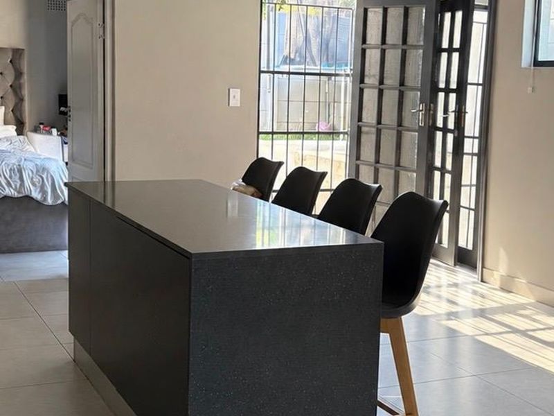 Open plan living area featuring a modern dark kitchen island, tiled flooring, and direct access to the exterior through classic french doors.