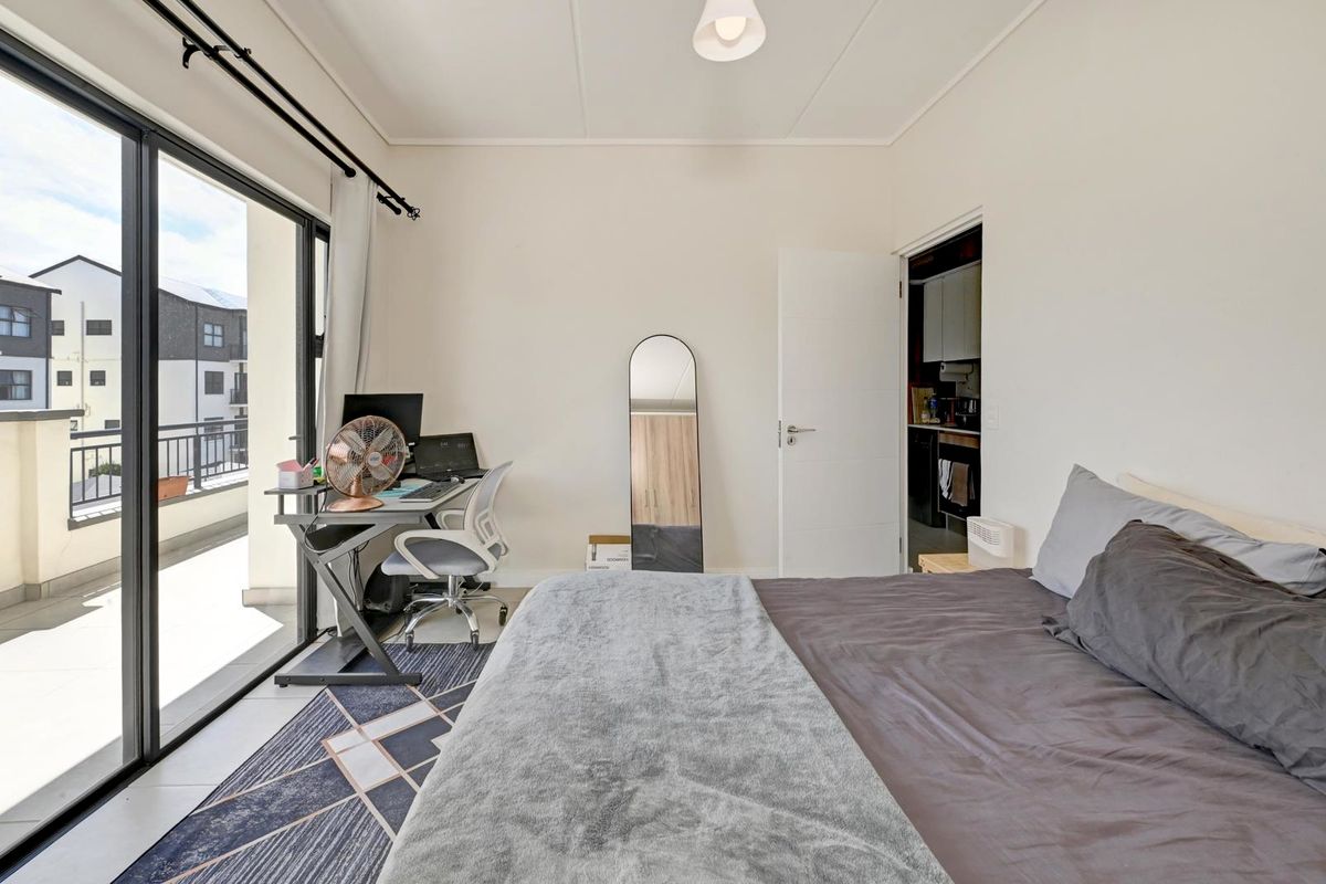 A bright bedroom featuring tiled flooring and a large sliding glass door providing direct access to a private balcony.