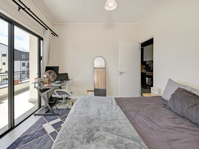 A bright bedroom featuring tiled flooring and a large sliding glass door providing direct access to a private balcony.