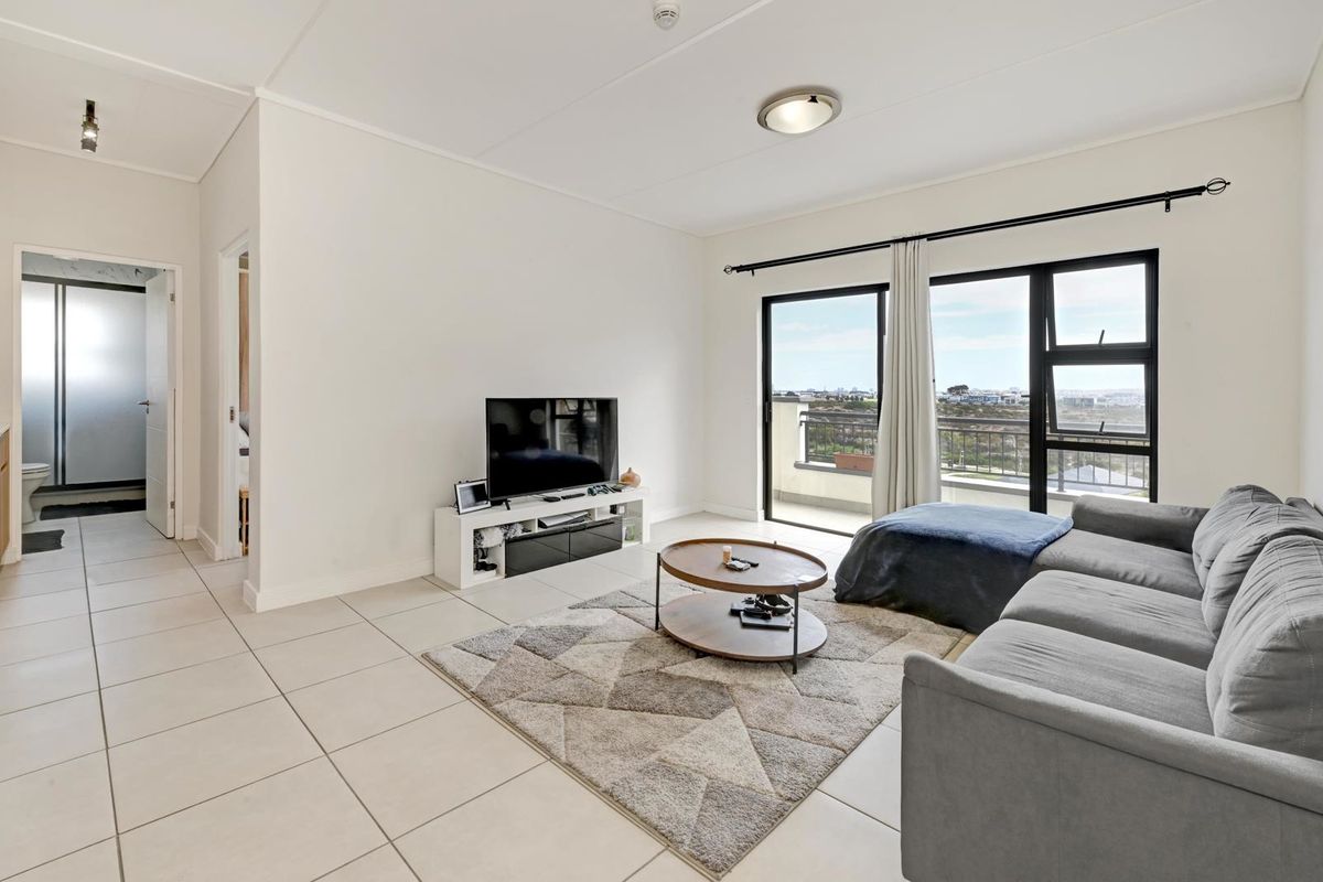 Bright living room featuring neutral tiled flooring and large sliding glass doors that provide natural light and direct access to the balcony.