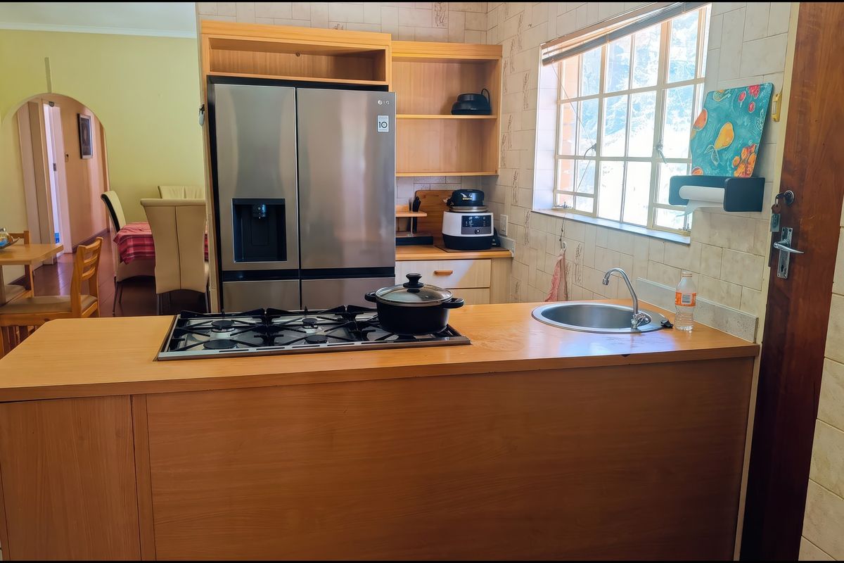 A functional kitchen featuring a wooden island with a built-in gas hob and sink, complemented by tiled walls and integrated cabinetry.