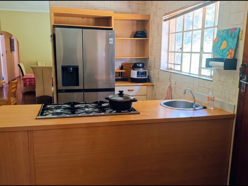 A functional kitchen featuring a wooden island with a built-in gas hob and sink, complemented by tiled walls and integrated cabinetry.