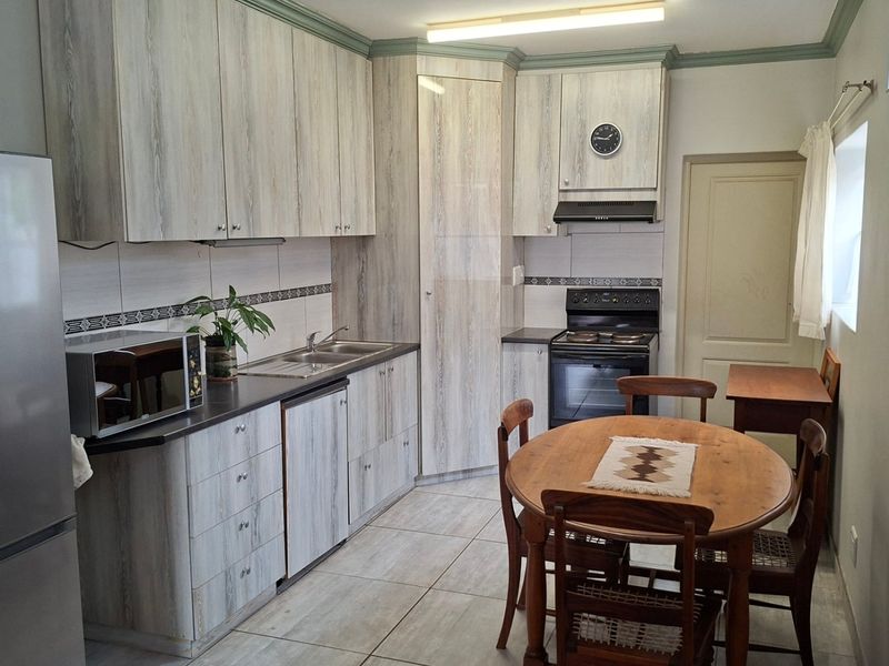 A functional kitchen featuring light wood-grain cabinetry, tiled flooring, a tiled backsplash, and a built-in oven with an extractor fan.