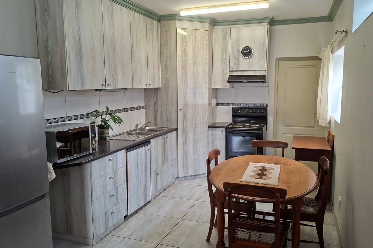 A functional kitchen featuring light wood-grain cabinetry, tiled flooring, a tiled backsplash, and a built-in oven with an extractor fan.
